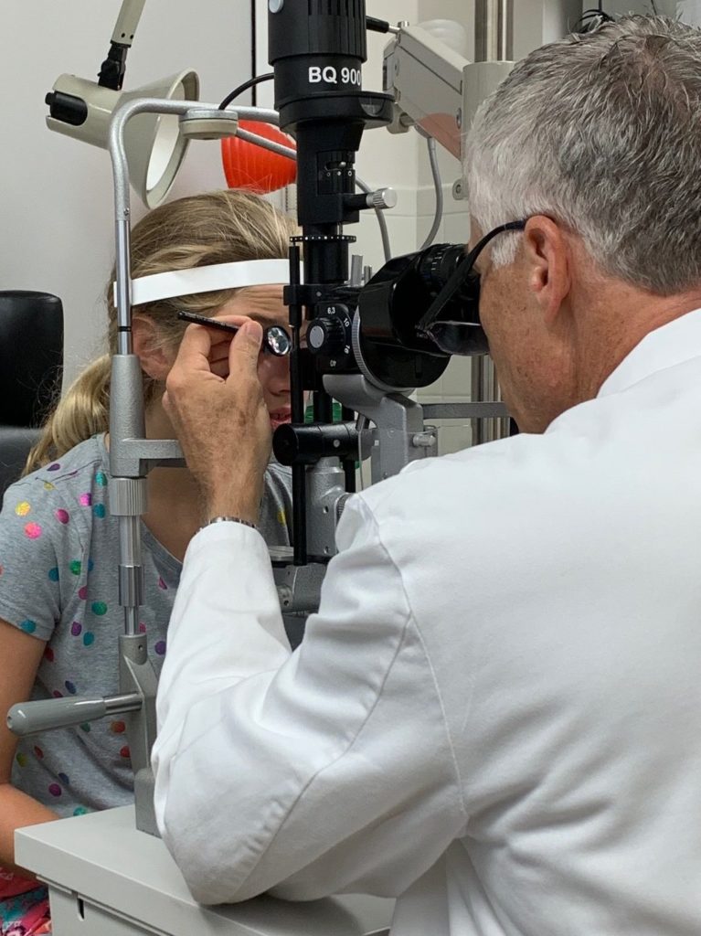 Male ophthalmologist is examining the eyes of a young female patient