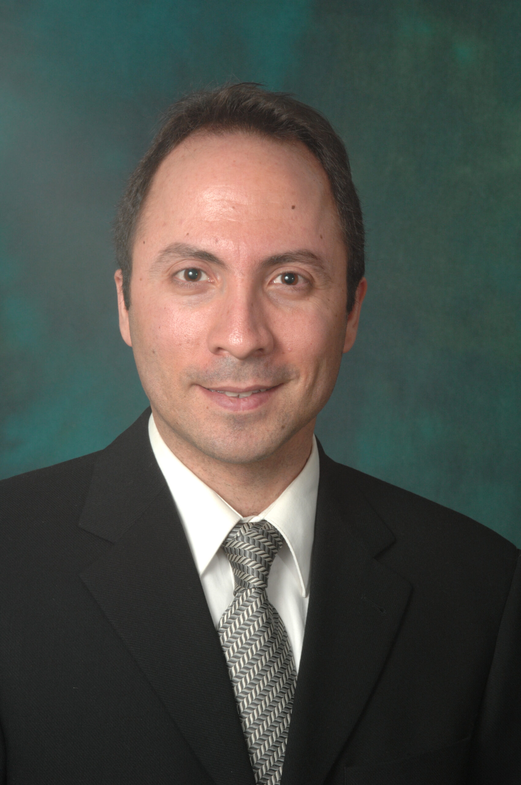 Professional picture of Ali Djalilian.  He is in a black suit with a white shirt and a tie. 